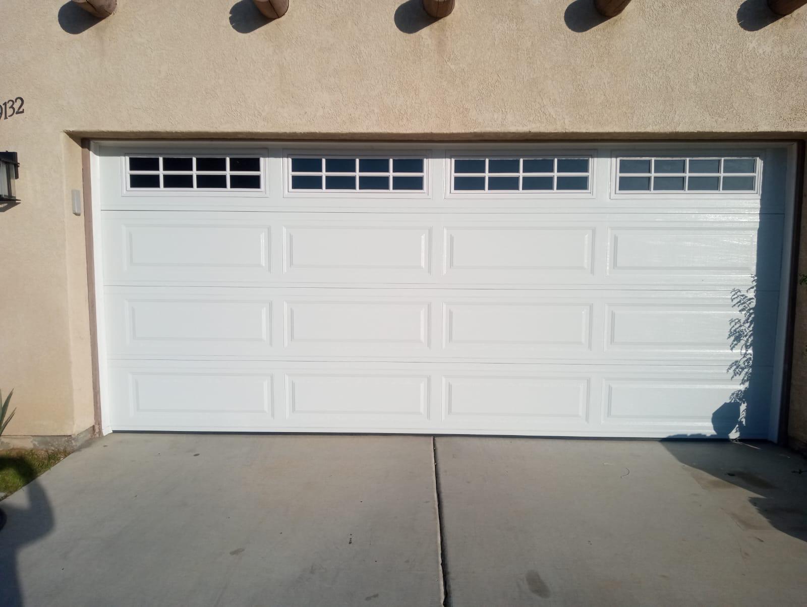 New white steel garage door with colonial-style window inserts installed in Indio